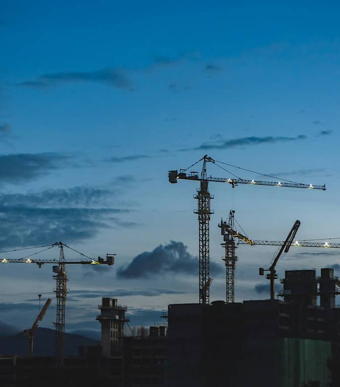 Byggekraner på en byggeplads i skumringen